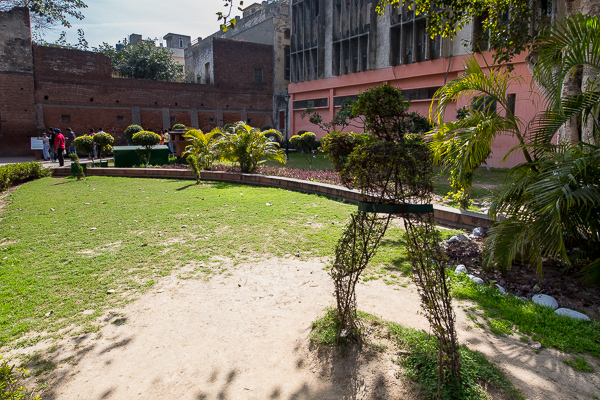 This shrub has been trimmed into the shape of a soldier holding a gun. If you look at the brick wall on the left-side of the photo, you will see white boxes. Within those boxes are the bullet holes that riddle the buildings. 